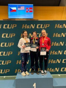 Three women stand on a podium.