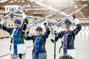 Three women holding their rifles above their heads 